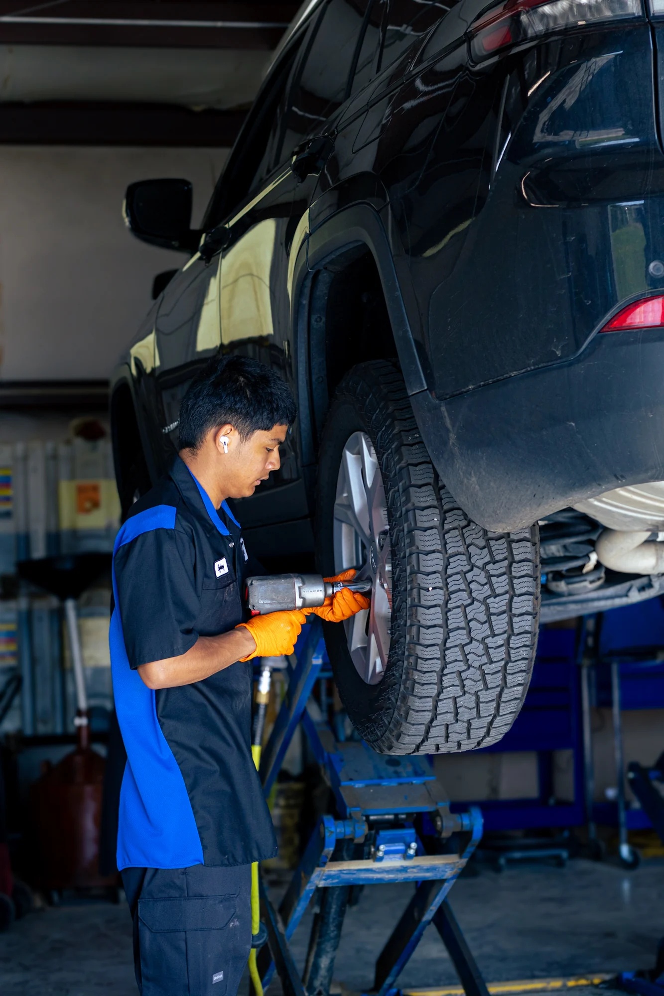 A Chrysler Corner technician using an impact wrench on a lifted vehicle