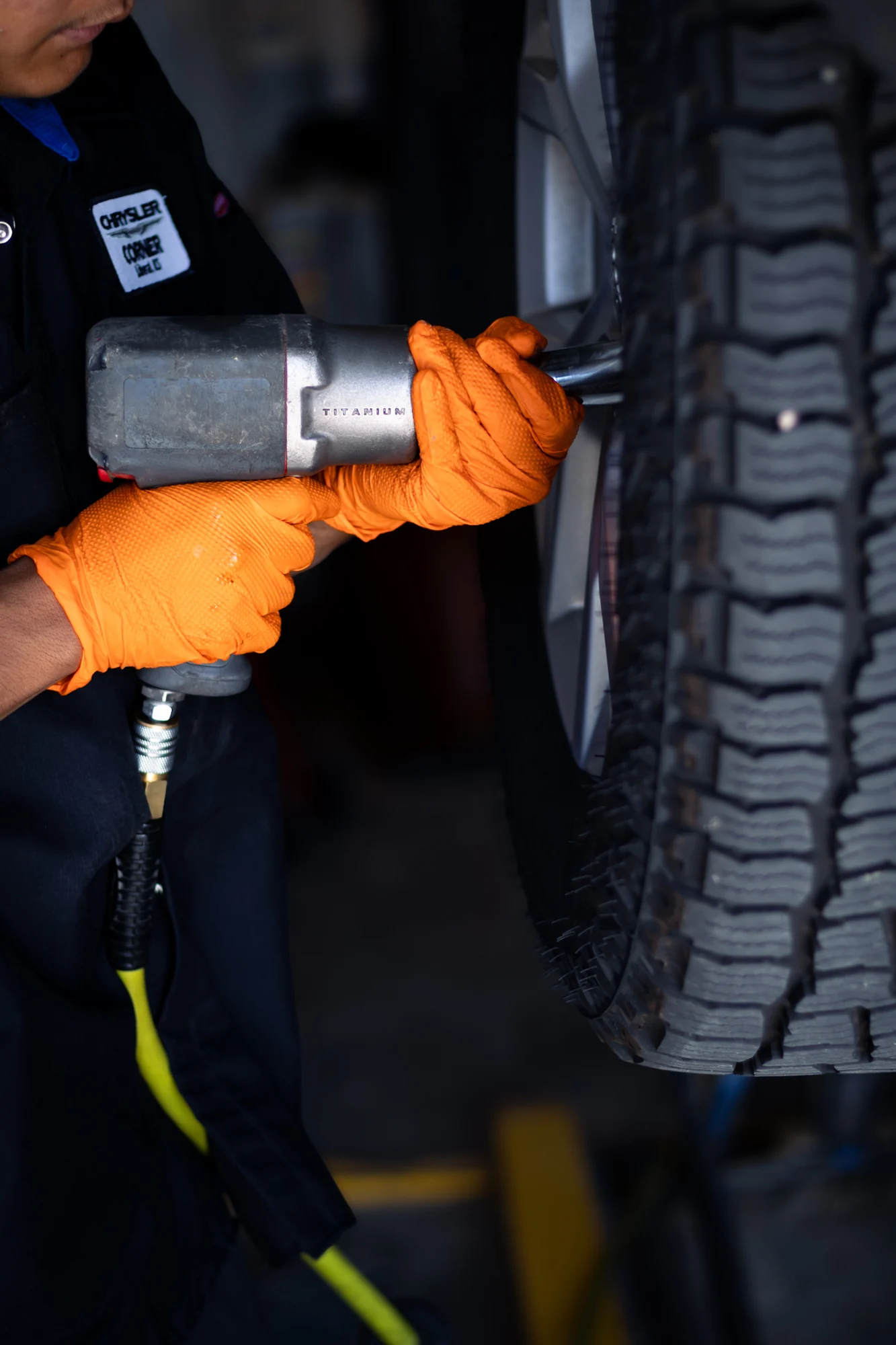 Gloved hands using an impact wrench on a truck wheel at Chrysler Corner