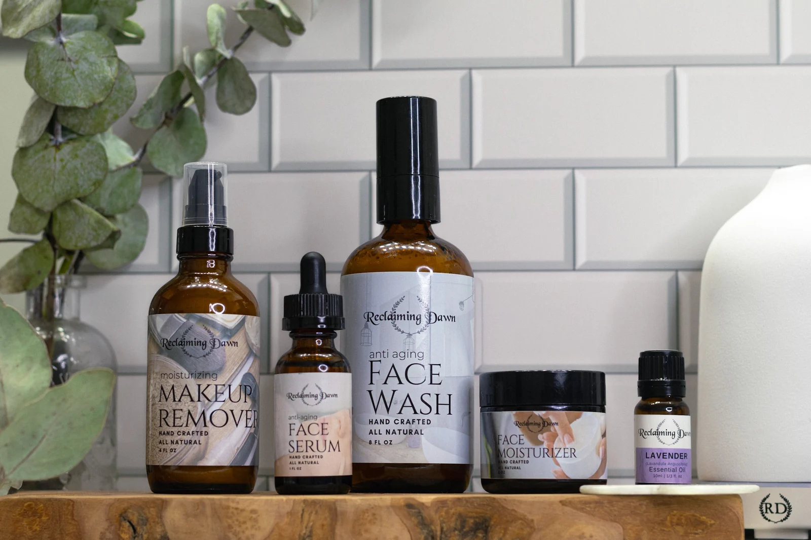 Five Reclaiming Dawn products lined up on wood with eucalyptus