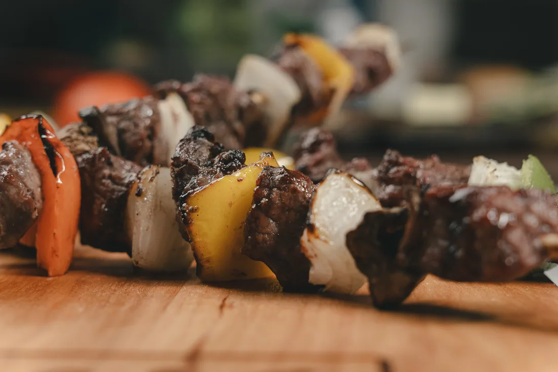 Close-up of grilled A&K beef skewers with peppers and onion