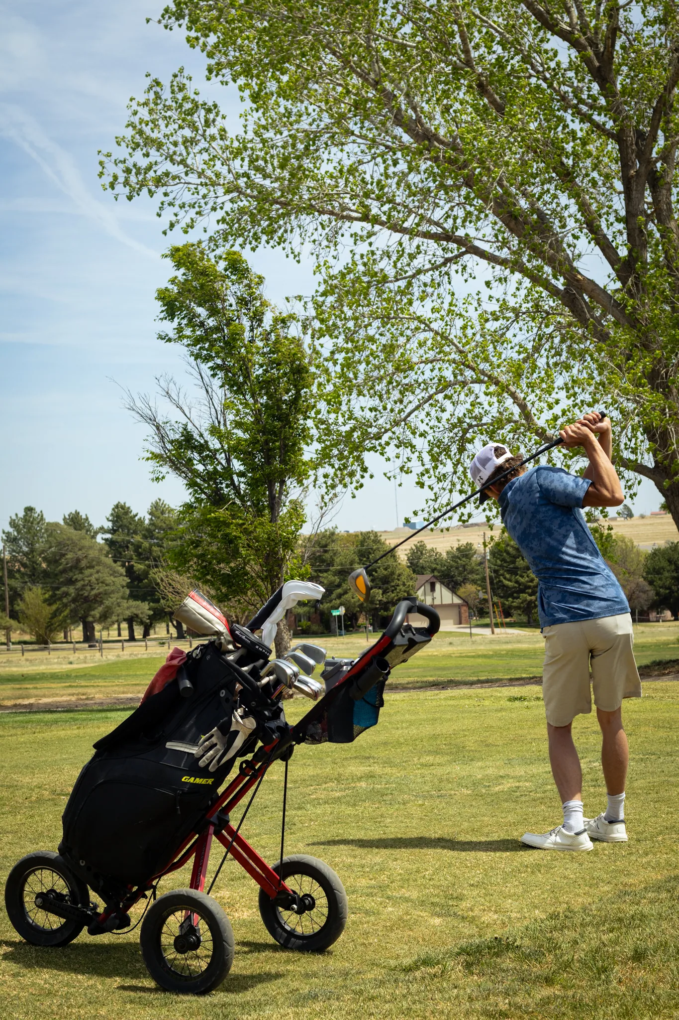 A golfer mid-swing with a push cart at Bentwood Golf Course