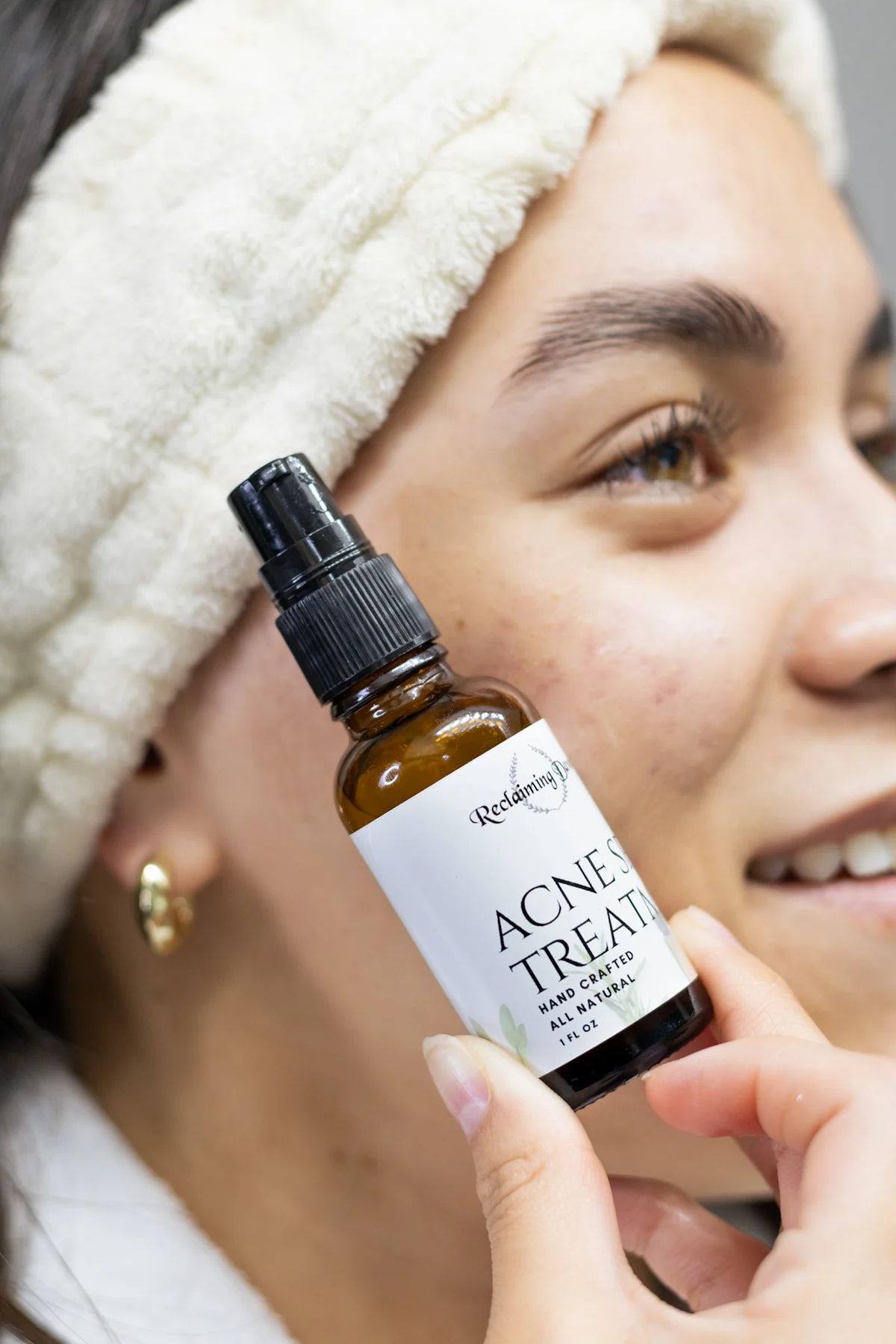 Reclaiming Dawn acne treatment held beside a model's face