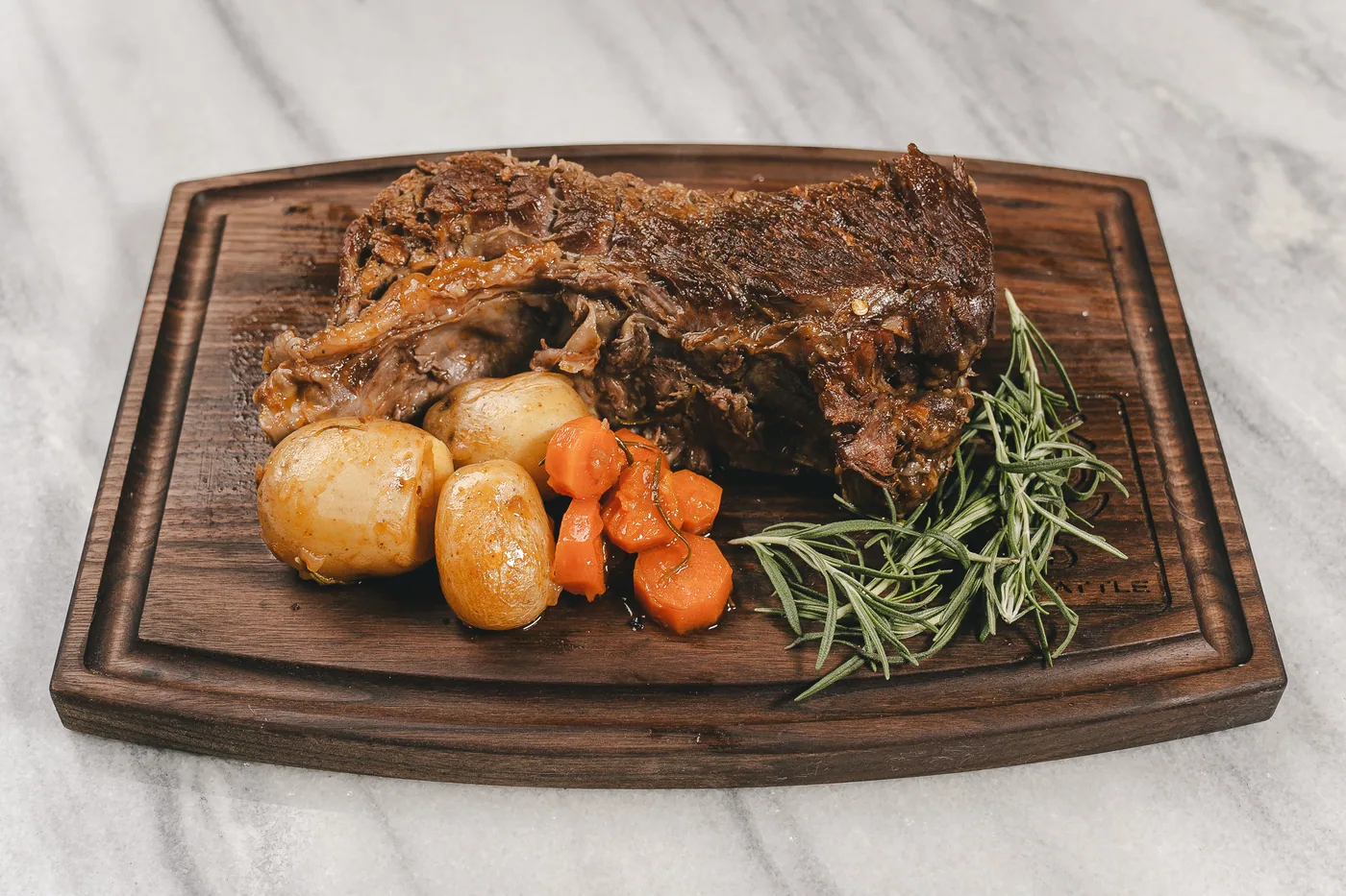 A&K beef pot roast plated with potatoes, carrots and rosemary