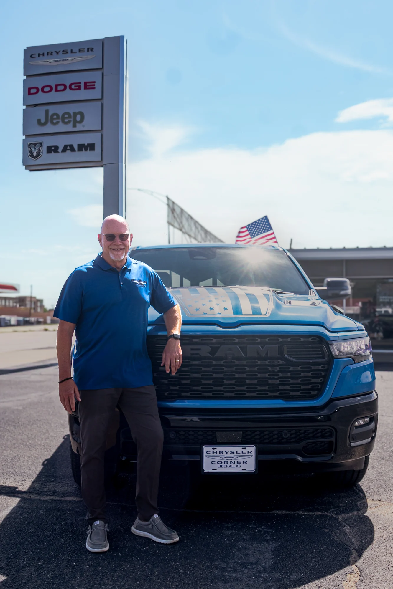 A Chrysler Corner team member beside a RAM truck at the dealership pylon