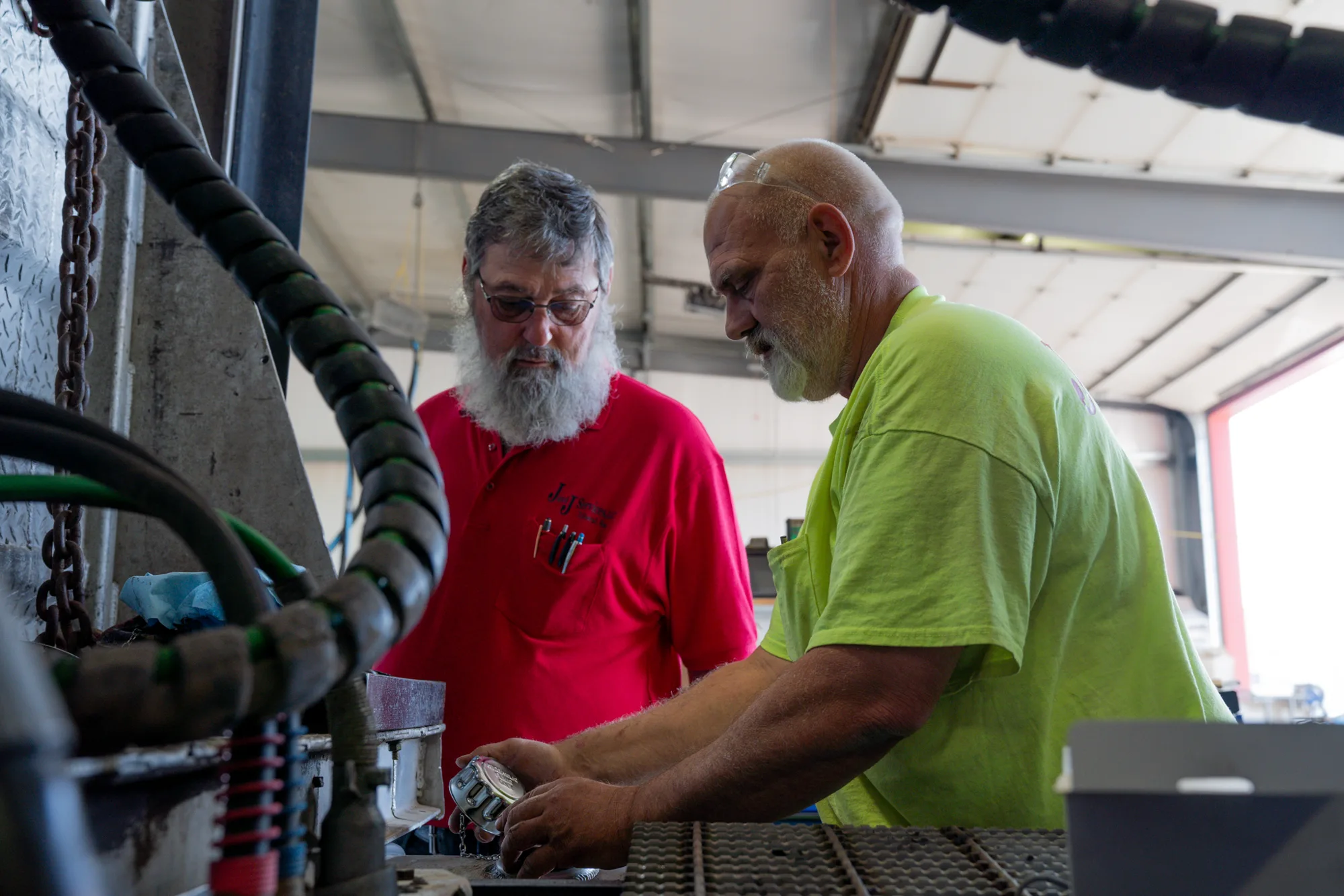 Two J and J Services LLC crew members working on the hose deck of a vacuum truck