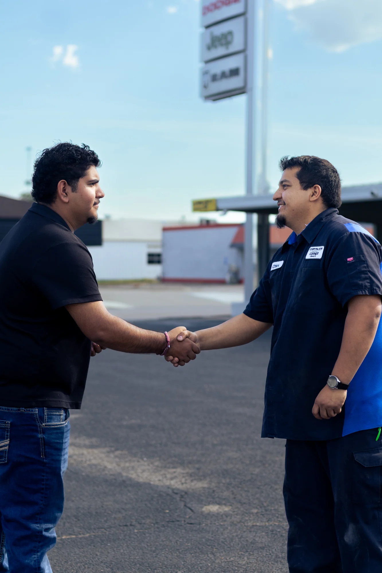 A Chrysler Corner service advisor shaking hands with a customer on the lot