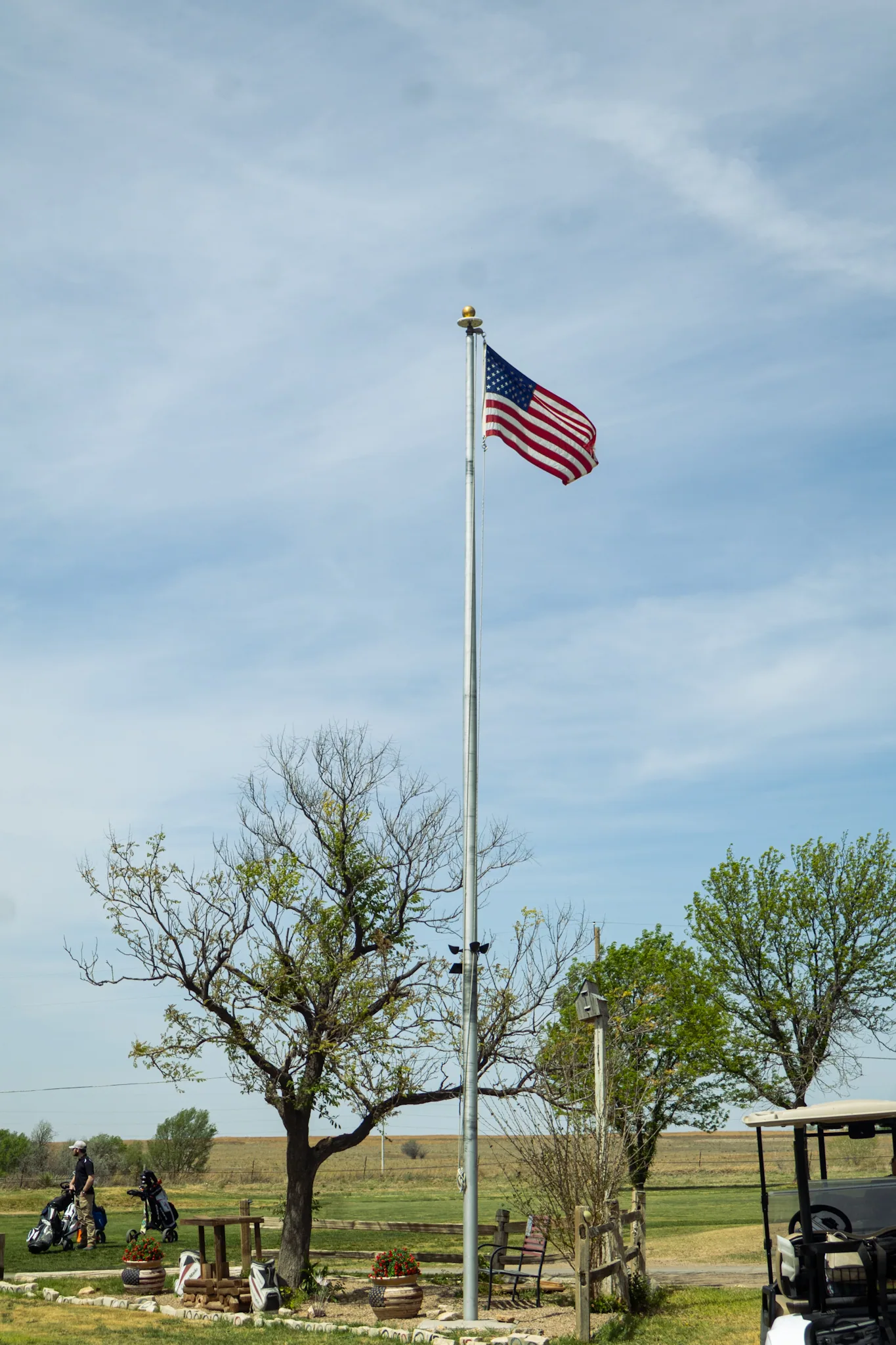 Flag pole, cart and players during an event at Bentwood Golf Course